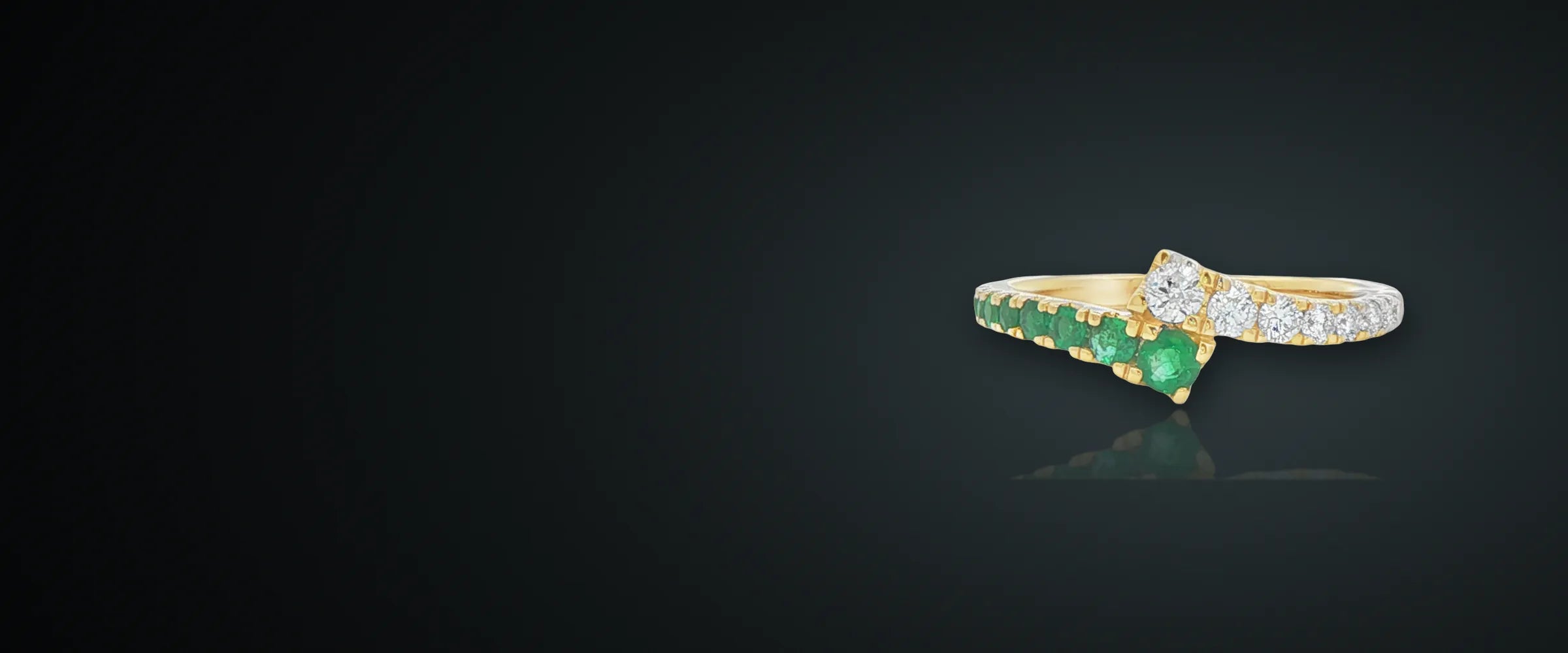 Emerald and diamond bypass ring in 14 karat yellow gold